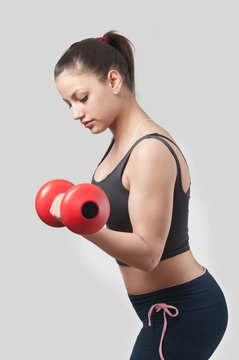 Strong attractive girl exercising with weights.