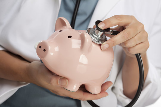 Doctor Holding Stethoscope to Piggy Bank