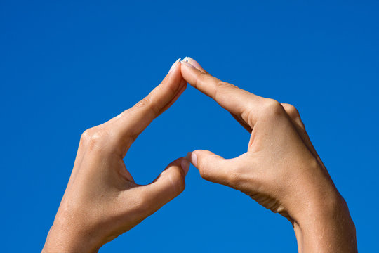 Heart shaped from hands against clear blue sky