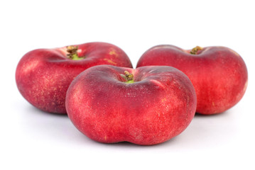 Three red flat peaches