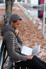 Man sitting on a Bench with netbook smiling