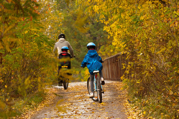 Family cycling outdoors, golden autumn in park