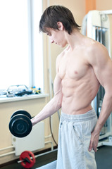 Powerful muscular man lifting weights in gym