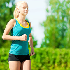Fototapeta premium Young woman running in green park