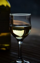 Weinglas mit Weisswein und Flasche am Abend