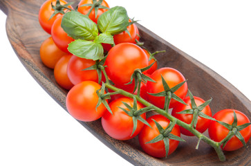 Cherry tomatoes with basil in wood plate