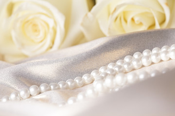 Pearl beads and cream rose on the silk background