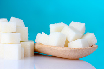 refined sugar in wooden spoon on blue background