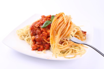 Spaghetti bolognese on a plate being eaten with a fork