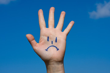 Human palm with sorrow pattern on blue sky background