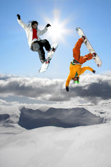 Naklejka na ściany i meble Snowboarders jumping against blue sky