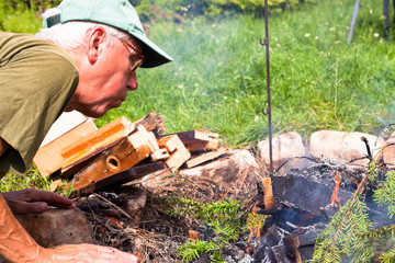 Senior man making bonfire