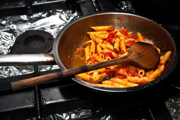 Penne arrabiata in a pan ready to heat up in a restaurant kitchen.