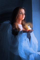 Portrait of an angel with a candle standing near the window.