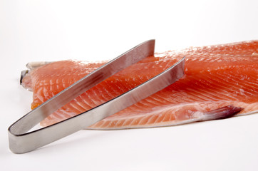 Lachsfilet und eine Grätenzange um Gräten zu entfernen