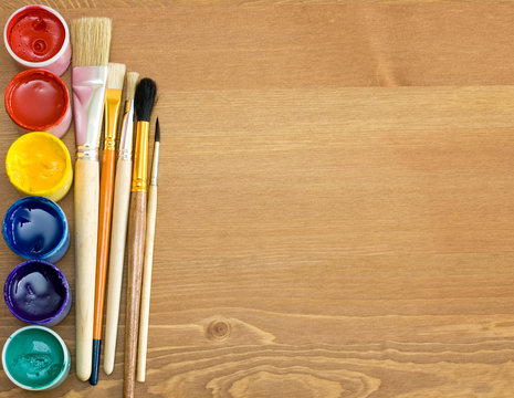 paints and brushes on wooden table