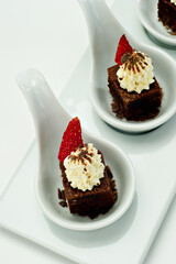 Chocolate brownie Dessert on white porcelain tasting spoons