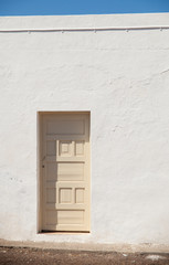 architectural abstract - cream-colored door in a bright white wa