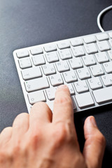 A man's hand typing on a keyboard.