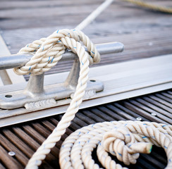 White mooring rope tied around steel anchor on boat or ship.