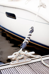 A white yacht moored with a line tied around a fixing