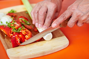 Senior woman's hands cutting vegetables