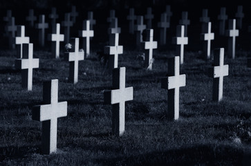 Rows of crosses in cemetery at night