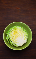 Image of white cabbage in a deep plate over wooden background