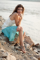woman sitting on stone near water