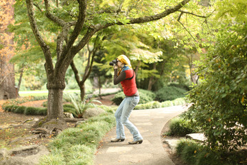 Obraz premium Pretty girl with a camera at a park.