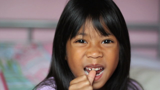 Asian Girl Wiggling Her First Loose Tooth