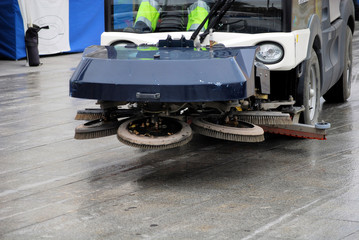 car sweeps dust and washes a stone floor in the street  cities o