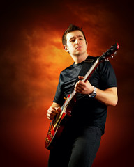 Rock guitarist play on the electric guitar, orange sky backgroun
