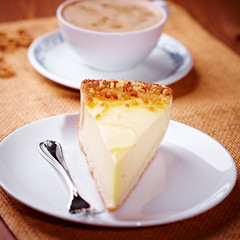 Cheesecake and a cup of cappuccino in background