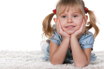 Smiling little girl lying on the carpet