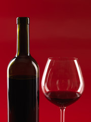 bottle of wine, glass on red background
