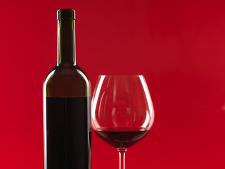 bottle of wine, glass on red background
