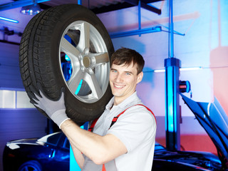 Motor mechanic working in a garage to change a winter tyre