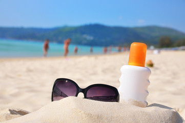 Sunglasses and protection lotion on the beach