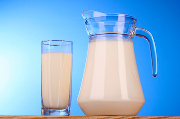 Pitcher and Glass with milk on blue background