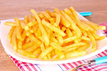 French fries on a plate and cutlery on a wooden background