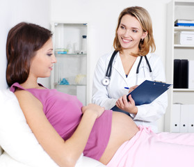 Pregnant young woman with doctor at clinic - Powered by Adobe