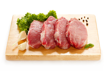 Raw pork on cutting board and vegetables