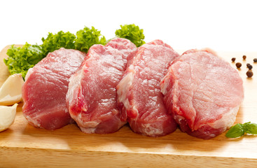 Raw pork on cutting board and vegetables
