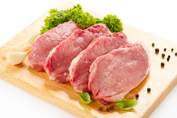 Raw pork on cutting board and vegetables