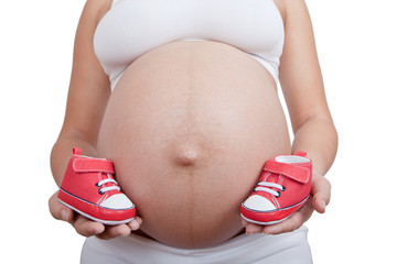 Pregnant woman hold in hand red baby boots