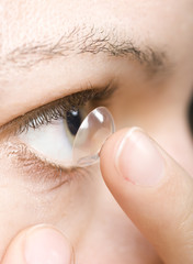 woman inserting a contact lens into the eye
