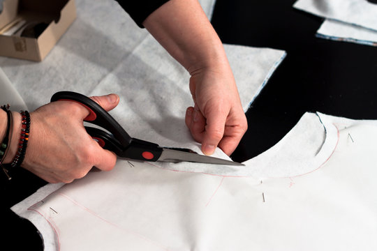 Woman hand cutting fabric after a sewing pattern