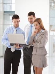 Young businesspeople looking at laptop screen