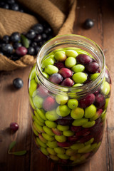 Olives in Brine (with Water and Salt in Glass Jar) on Wood